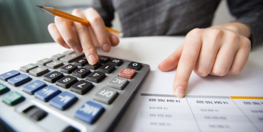 closeup of accountant hands counting on calculator scaled